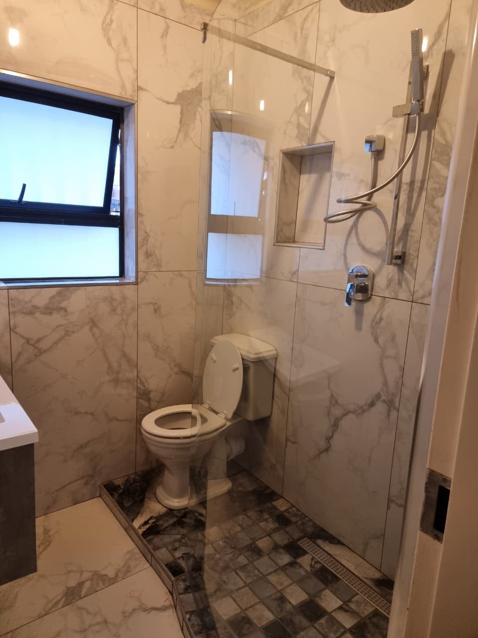 Renovated marble-tiled bathroom shower and toilet