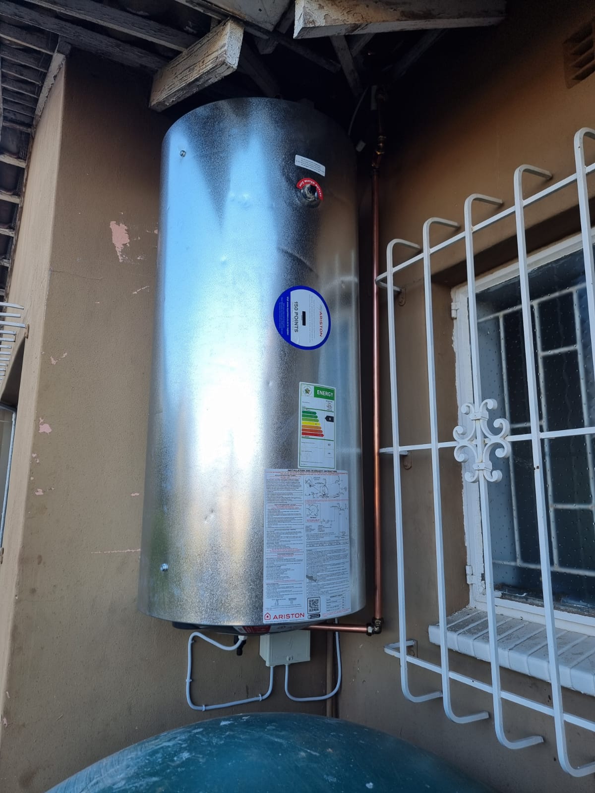 Geyser cylinder installed in a roof eave with copper pipework