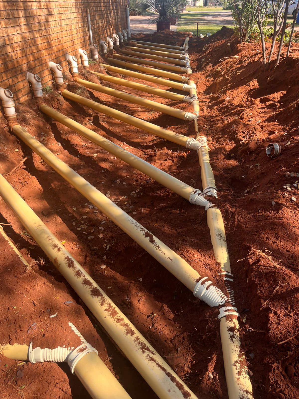 New sewer pipe trenching and laying along a property boundary
